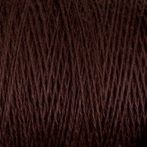 A close-up image of a spool of Supreme Corp's Homestead 8/2 Cotton Yarn in dark brown, showcasing the intricate texture of the fibers wound around the mini-cone. The intertwined threads form a pattern of diagonal lines, with subtle variations in tone and texture, demonstrating how this weaving yarn can be both functional and beautiful.