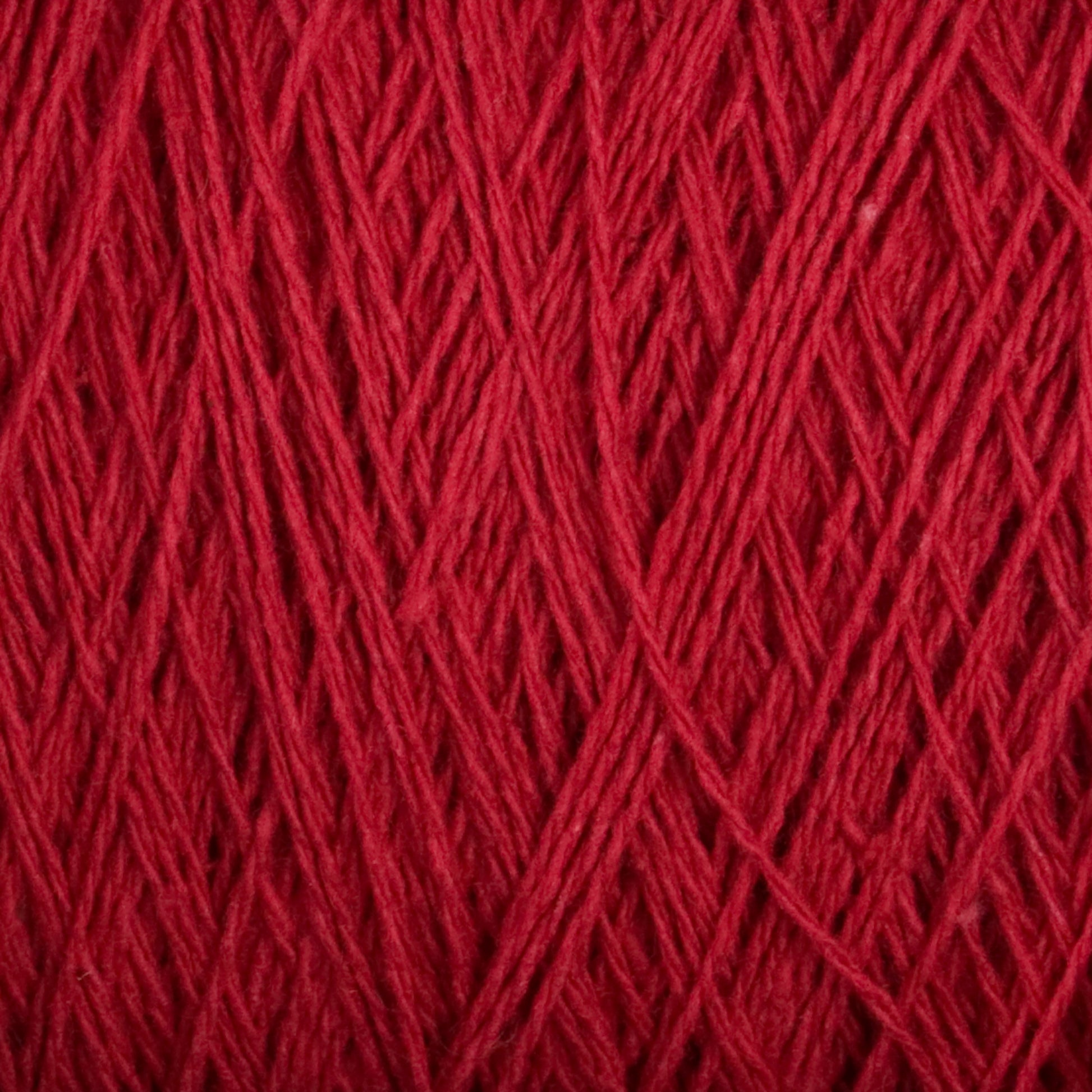 Close-up view of a textured red yarn. The strands are interwoven, showcasing the intricate weaving pattern. This Supreme Corp Homestead 8/2 Cotton Yarn | Large Cone focuses on the rich, solid red color and its fine, slightly fuzzy texture, all while being machine-washable for your convenience.