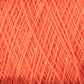 Close-up image of a tightly wound ball of coral-colored, versatile yarn. The thin strands of Homestead 8/2 Cotton Yarn from Supreme Corp are densely packed, creating a textured pattern of intersecting lines and subtle shadows, perfect for weaving projects.