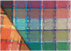 The Homestead Cotton Color Gamp from Halcyon Yarn is a vibrant woven textile showcasing a complex, multicolored plaid pattern in shades of red, orange, yellow, green, blue, and purple. This fabric could be ideal for creating a lively set of kitchen towels. It is slightly folded at the bottom left corner, demonstrating the continuity of the pattern across the fold.