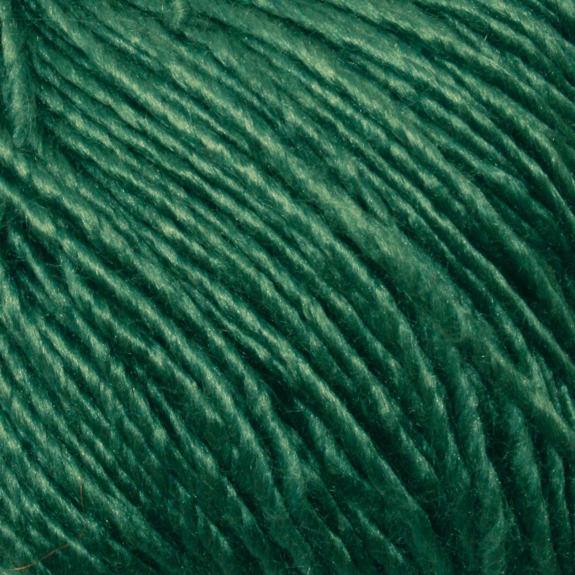 Close-up image of Gemstone Soft Twist Silk Yarn by Halcyon Yarn, showcasing its smooth, glossy texture and tightly spun fibers. The silky material, reflecting light slightly, emphasizes the individual strands and the sheen of the Halcyon Yarn's soft twist silk.