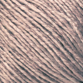 Close-up image of Halcyon Yarn's Gemstone Soft Twist Silk Yarn in light beige. The yarn fibers appear slightly shiny and are tightly twisted together, creating a smooth and delicate texture.