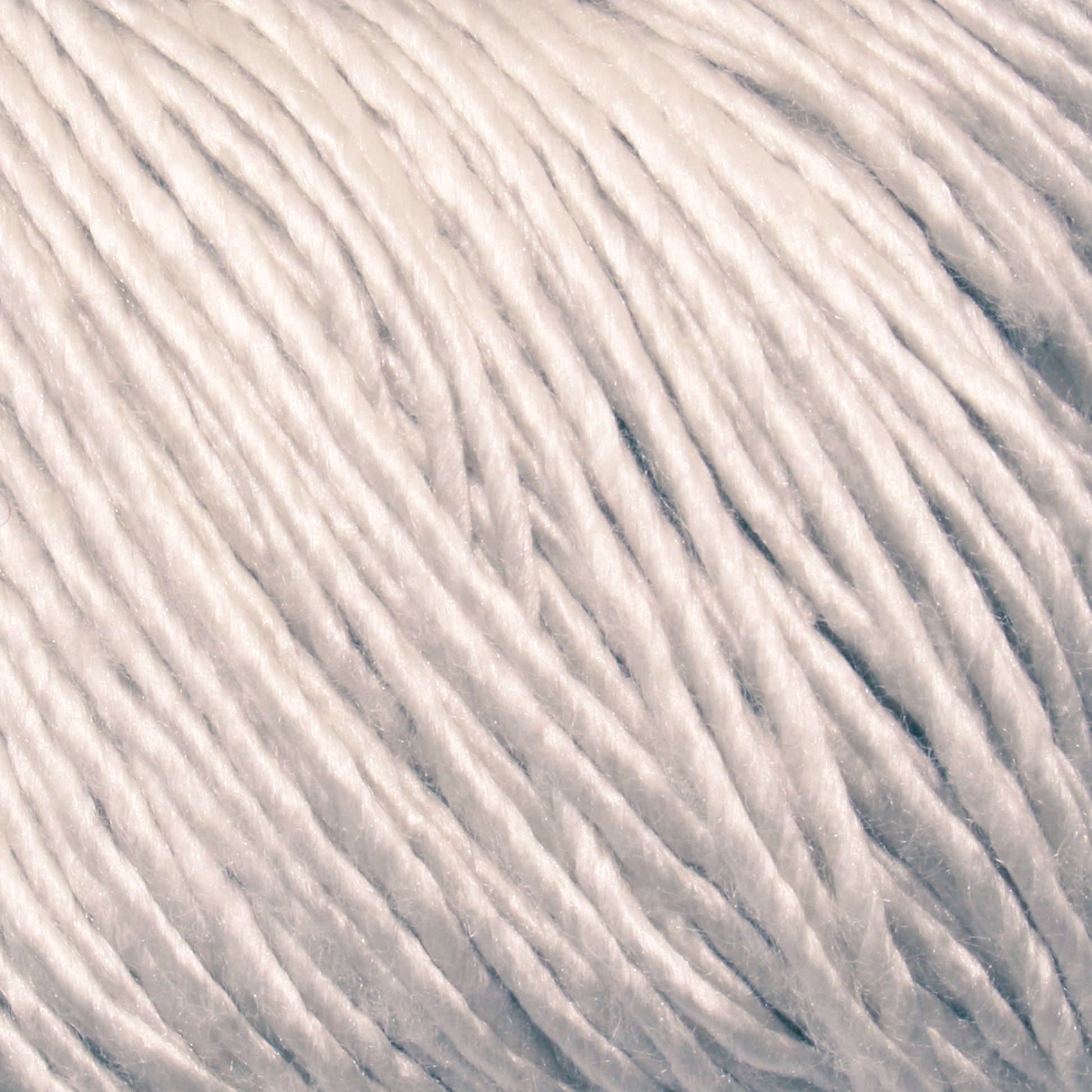 Close-up image of Gemstone Soft Twist Silk Yarn by Halcyon Yarn, showcasing its intricate and soft fibers twisted together. The yarn appears thick and slightly glossy, reflecting light. The detailed texture emphasizes the smooth and intertwined threads characteristic of high-quality Gemstone Soft Twist Silk.