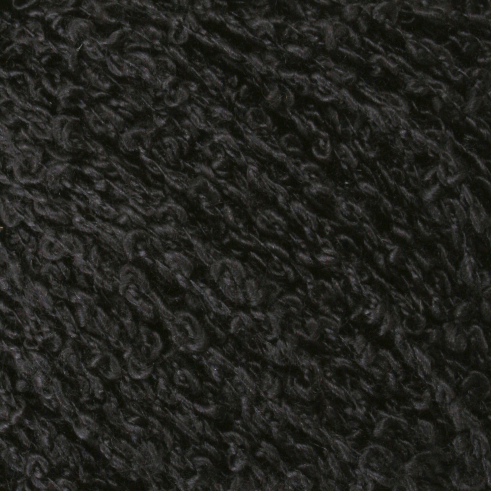 Close-up image of Gemstone Silk Bouclé. The black, curly wool texture showcases densely packed fibers, forming a wavy and intricate pattern that mirrors Halcyon Yarn's finest creations. The surface looks soft and plush, highlighting the natural, coarse details inherent in the wool's structure.