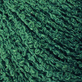 Close-up of green Gemstone Silk Bouclé from Halcyon Yarn, showcasing a tightly coiled and textured pattern. The yarn features a combination of smooth and slightly frizzy fibers, creating a rich, tactile surface. The color is a consistent deep green with subtle variations in shade, reminiscent of the luxurious aesthetics of Gemstone Silks, adding depth.