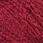 Close-up image of Halcyon Yarn's Gemstone Silk Bouclé in a rich, deep red color, showing intricate twists and loops of the fibers. The surface appears soft and plush, ideal for knitting or crocheting projects.