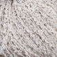 Close-up of a ball of bulky, textured, off-white yarn. The yarn, resembling Halcyon Yarn's Gemstone Silk Bouclé, has a soft and fluffy appearance with loops and curls, giving it a unique, curly texture.