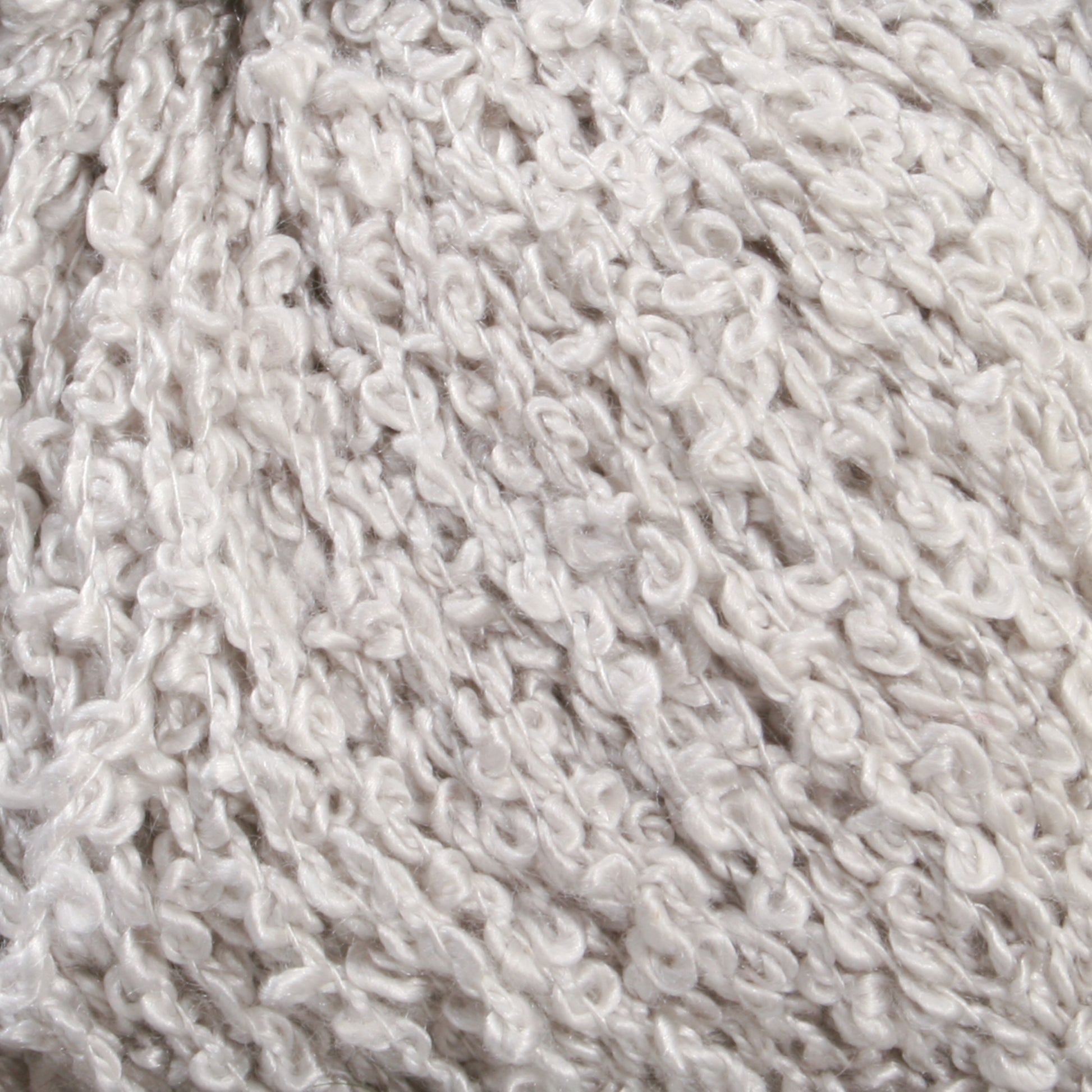 Close-up of a ball of bulky, textured, off-white yarn. The yarn, resembling Halcyon Yarn's Gemstone Silk Bouclé, has a soft and fluffy appearance with loops and curls, giving it a unique, curly texture.