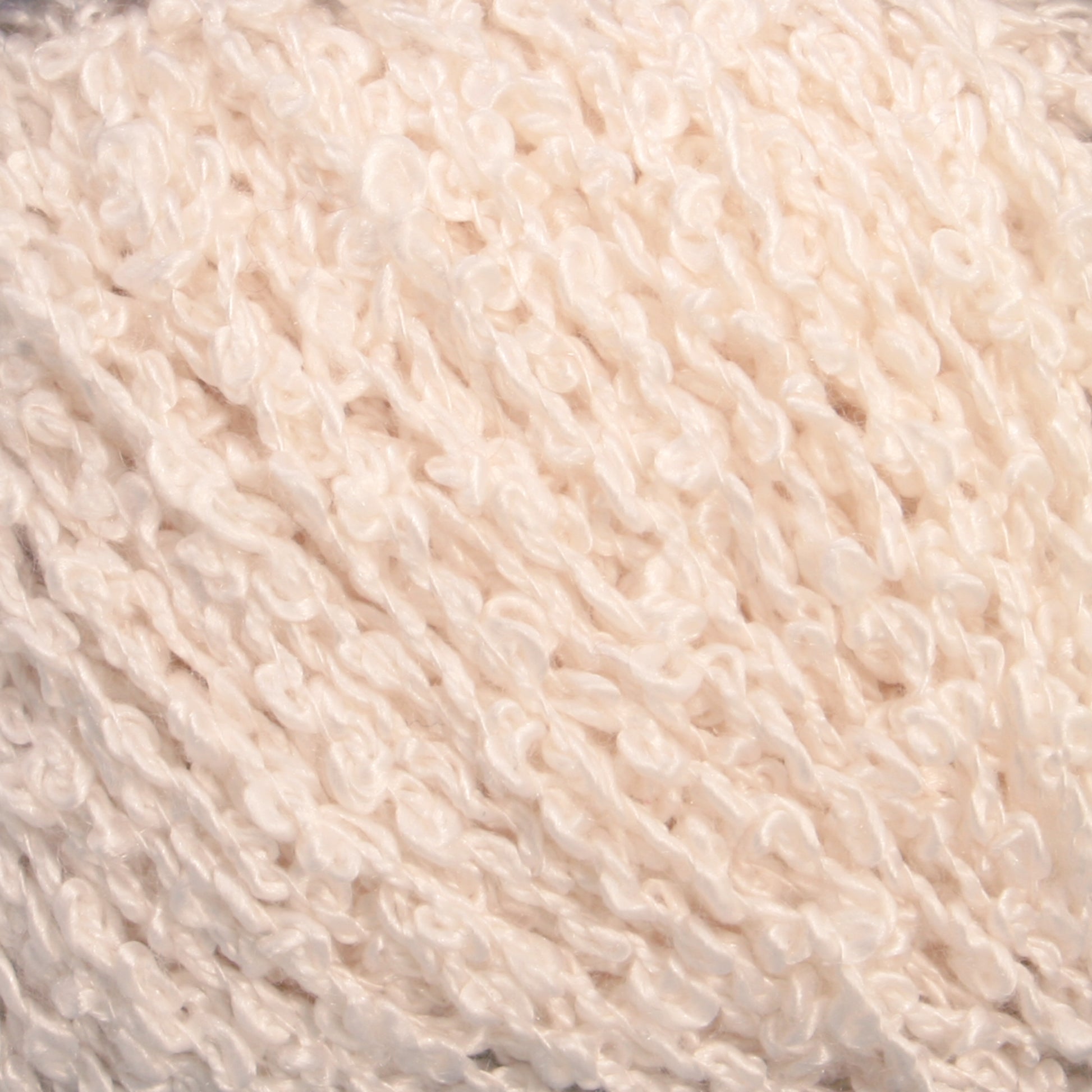 Close-up of a textured cream-colored yarn. The yarn appears to be soft and bulky, with a looped and slightly uneven surface, creating a fluffy and cozy appearance—reminiscent of the luxurious feel of Halcyon Yarn's Gemstone Silk Bouclé.