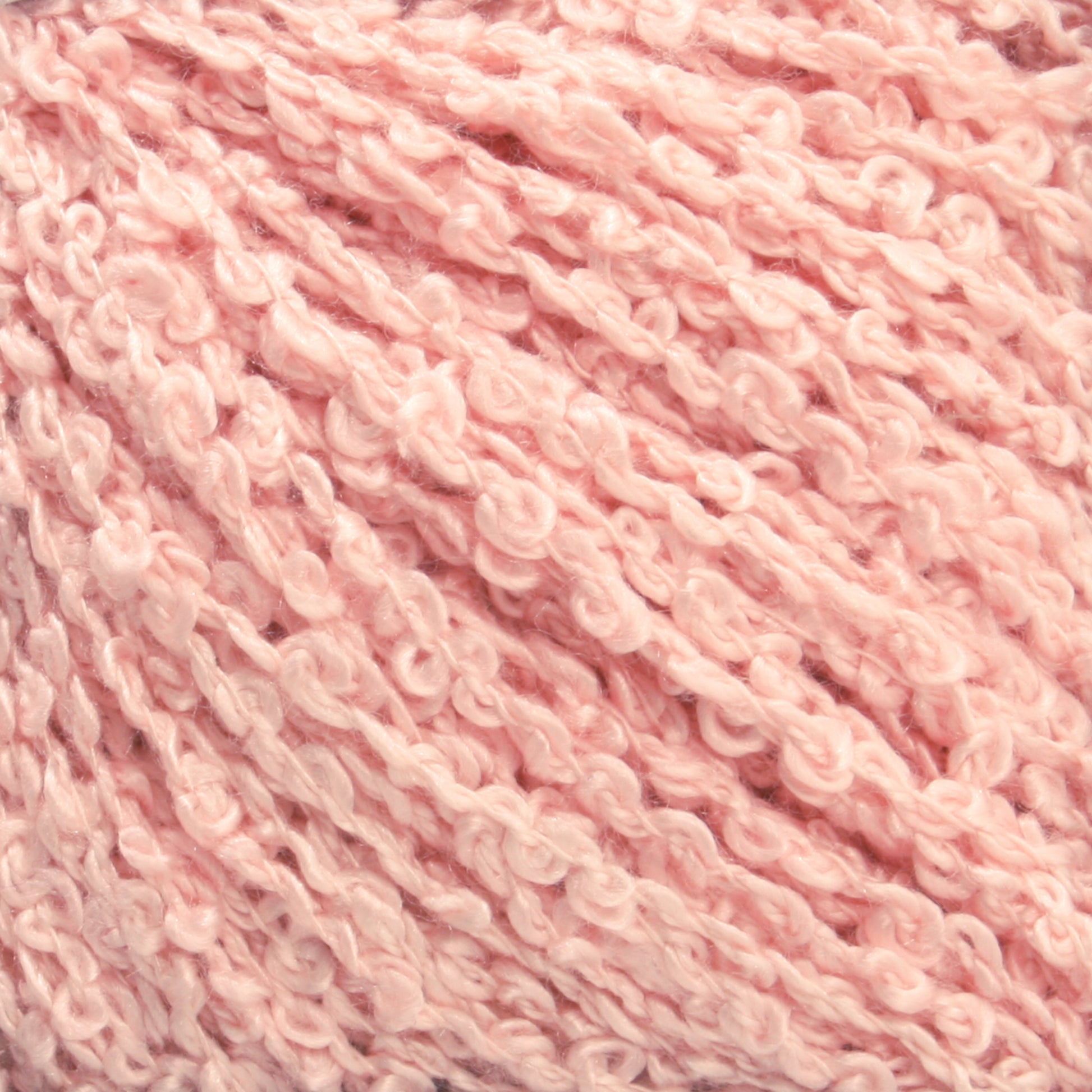 Close-up image of soft, pale pink *Gemstone Silk Bouclé* yarn by *Halcyon Yarn* with a textured, loopy, and curly appearance. The fibers are arranged in a dense, intertwined pattern, giving the yarn a cozy and fluffy look.