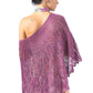 A woman stands with her back to the camera, wearing a beautiful Belarra Shawl by Twist Collective. The shawl features an intricate lace and cable pattern in a stunning shade of purple. Her hair is tied up in a bun, and she is dressed in a floral-patterned dress. The shawl drapes elegantly over her shoulders and down her back, offering a striking contrast to the ornamental grasses swaying nearby.