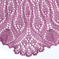 The Belarra Shawl by Twist Collective showcases an intricate knitting pattern crafted from a rich purple yarn. This exquisite design features ornate lacework with repetitive leaf-like motifs and scalloped edges, reminiscent of ornamental grasses. The delicate craftsmanship highlights the fine detail and texture of the knitted fabric.