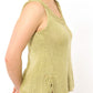 A person wearing the Twist Collective Papeda Camisole, a sleeveless, light green knitted top featuring decorative lace yoke edges and small side slits. The individual is smiling and standing with their hands behind their back, against a plain white background.