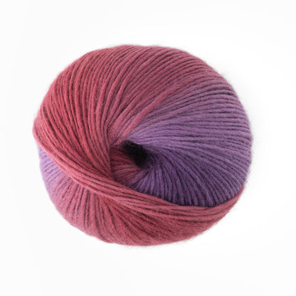 A ball of Louisa Harding Amitola Grande yarn by Knitting Fever / Euro Yarns, featuring a gradient from deep pink to purple with a spiral twist, is positioned against a plain white background.