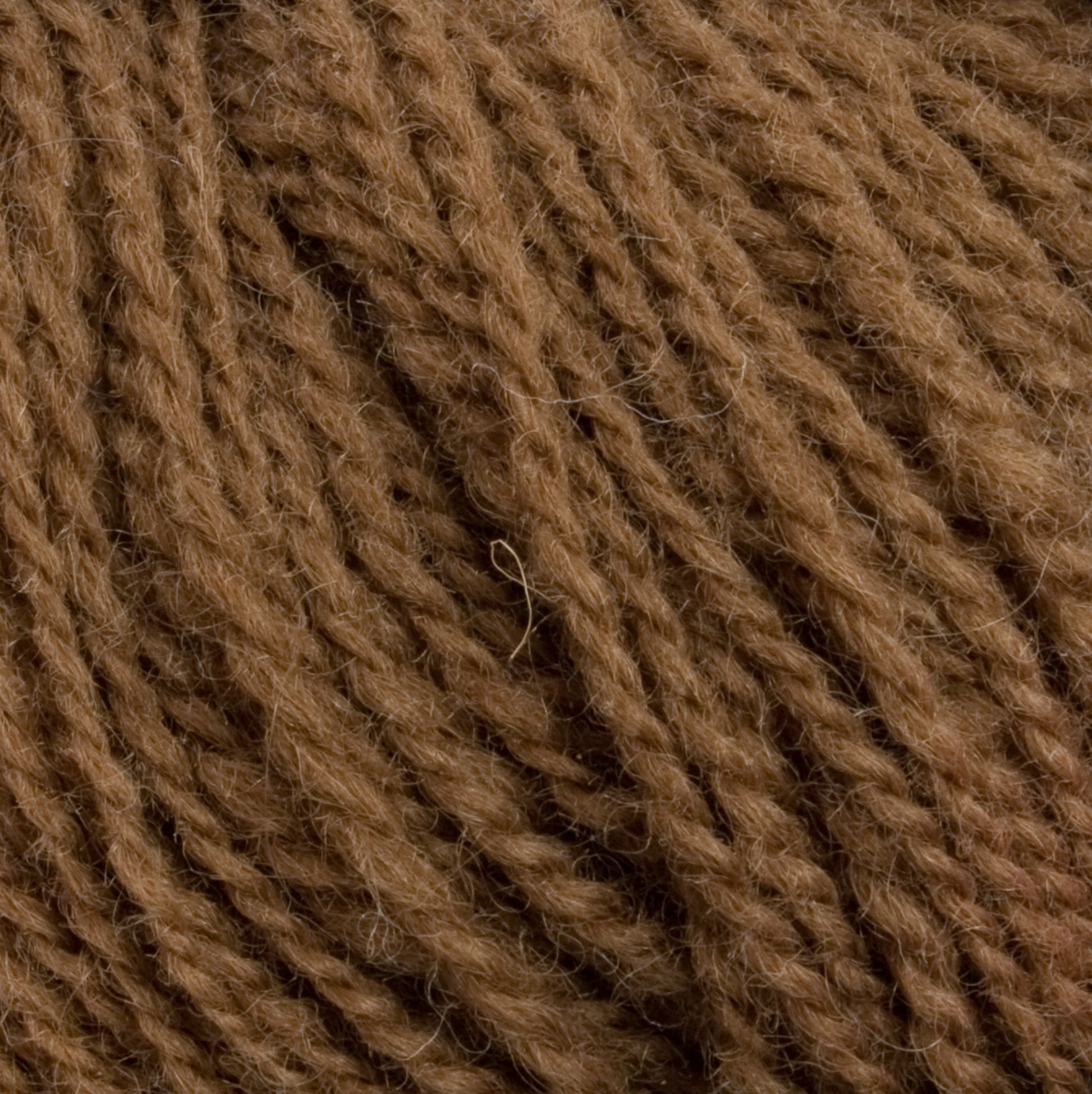 Close-up image of a ball of Halcyon Yarn's Victorian 2-Ply Wool Yarn in brown, featuring a soft and slightly fuzzy texture. The sport weight strands are thick and tightly wound, showcasing the individual fibers and overall woolly appearance, making it perfect for hand knitting.