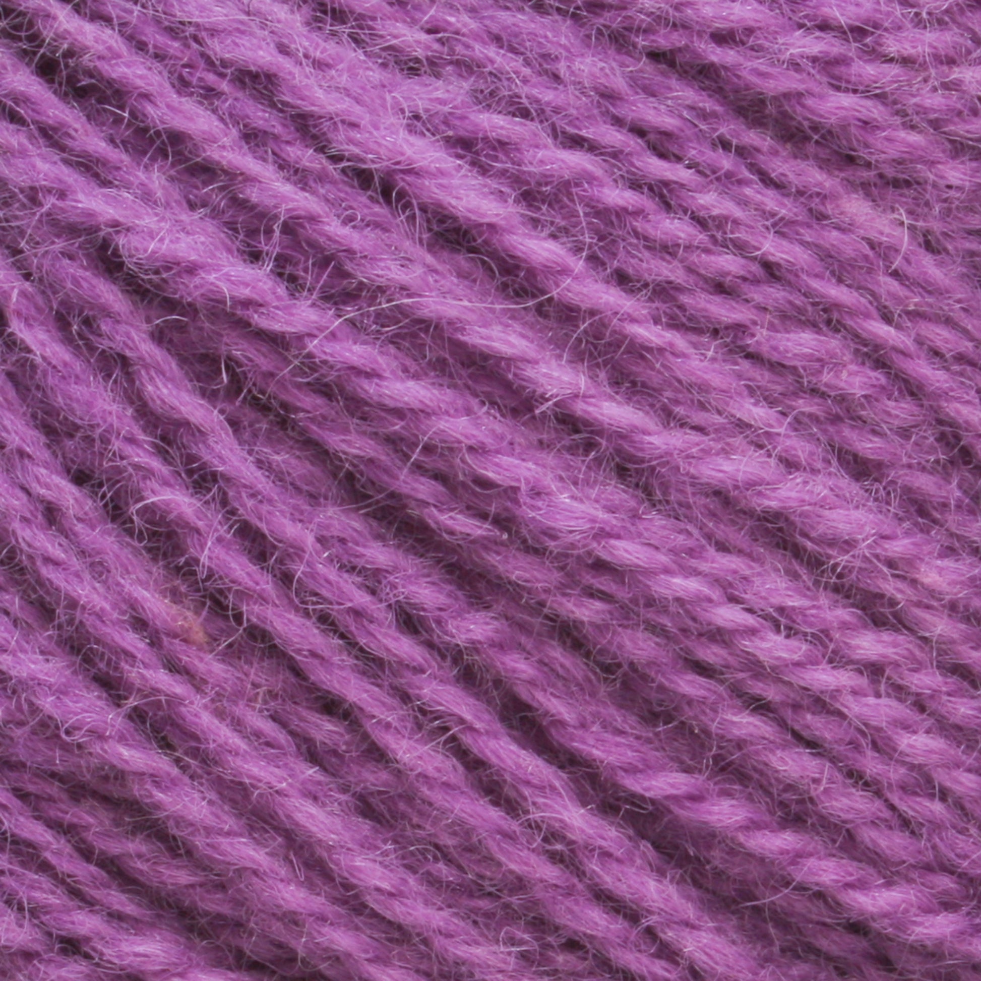 Close-up image of Halcyon Yarn's Victorian 2-Ply Wool Yarn in a rich purple hue, showcasing its visible fiber texture and strands. The yarn appears soft and slightly fuzzy with a consistent weave pattern, making it perfect for hand knitting projects.