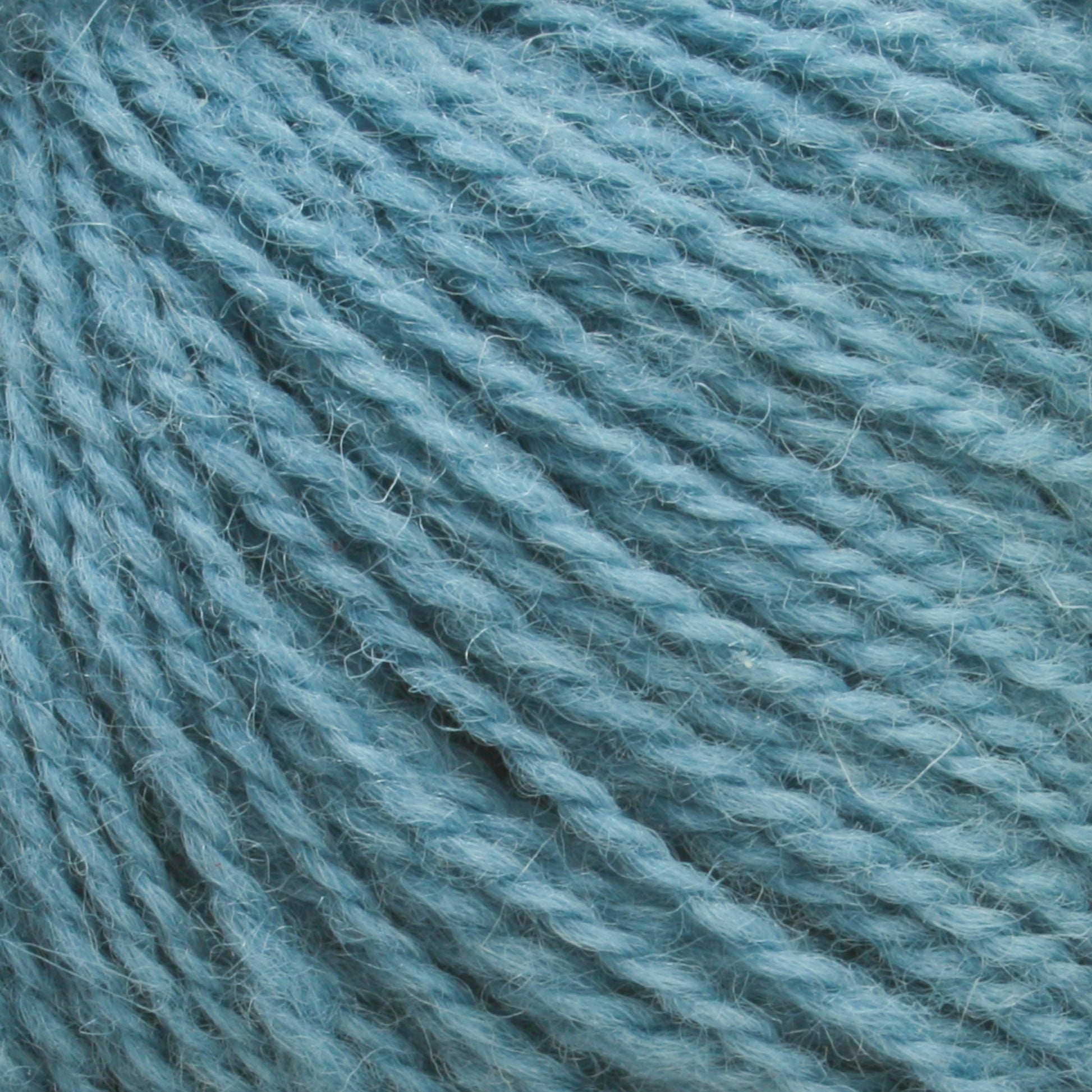 Close-up of light blue Victorian 2-Ply Wool Yarn by Halcyon Yarn showing its soft and textured strands. This sport weight yarn is tightly wound, displaying its fibers and slightly fuzzy surface, perfect for hand knitting.