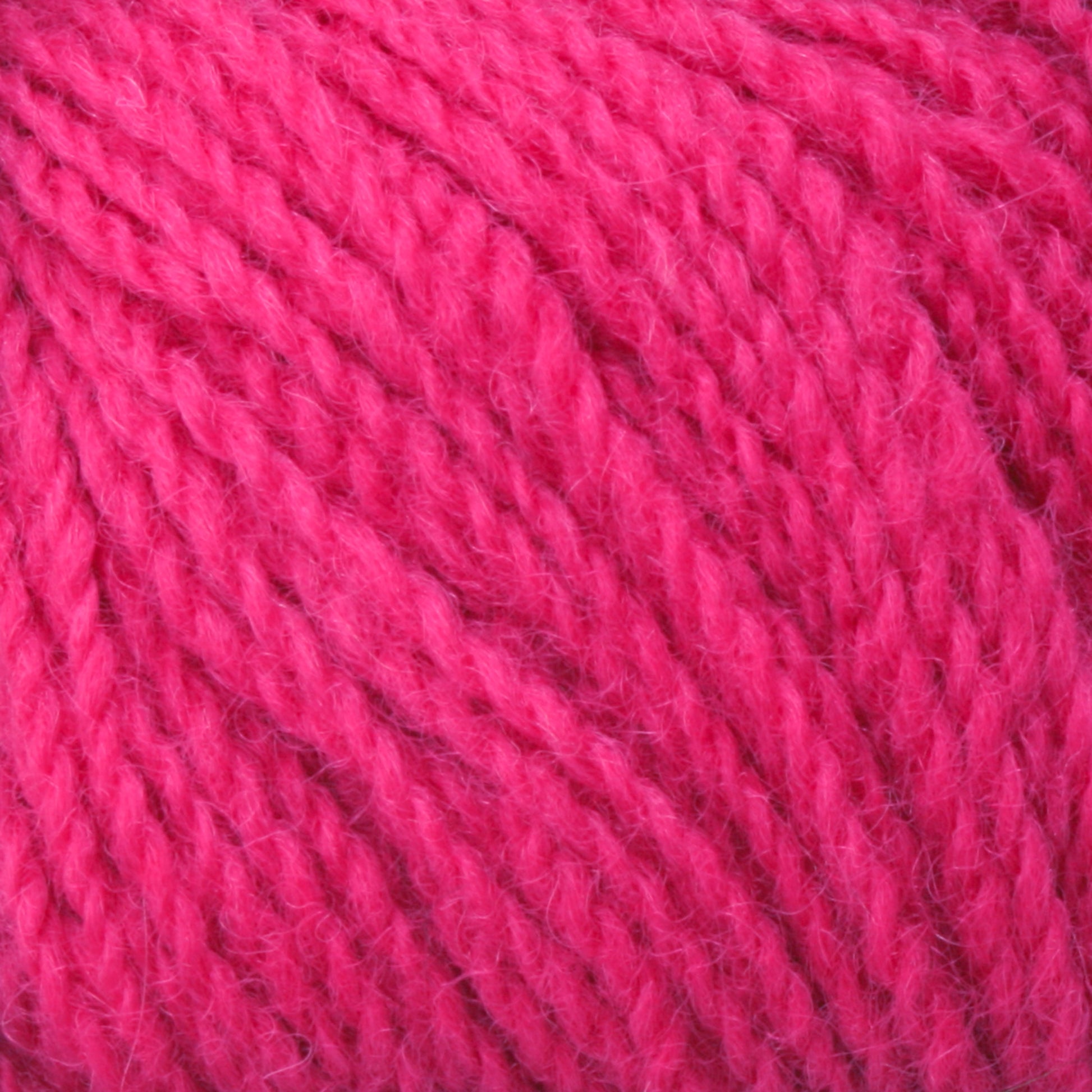 Close-up image of bright pink Victorian 2-Ply Wool Yarn. The thick, slightly fuzzy fibers of this Halcyon Yarn sport weight yarn are twisted together to form a plump and soft texture. The vibrant color and texture indicate it would be ideal for hand knitting cozy, colorful items.