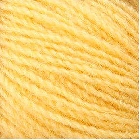 Close-up of a skein of Victorian 2-Ply Wool Yarn in yellow, from Halcyon Yarn. The texture of the sport weight yarn is clearly visible, showcasing its soft fibers and slightly twisted strands. The image highlights the cozy and warm appearance perfect for hand knitting projects.