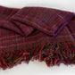 Introducing the Forest Glen Broken Twill Throw by Halcyon Yarn—a folded, multicolored wool scarf adorned with a plaid pattern and fringe ends. This exquisite scarf features an intricately woven broken twill design in shades of red, purple, and green. The harmonious blend of colors and detailed craftsmanship is beautifully showcased against a plain white background.