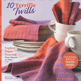 The cover of Long Thread Media's Handwoven Magazine May/June 2022 issue showcases orange and purple twill napkins along with a fabric swatch. The headline reads "10 Terrific Twills," highlighting articles on paper weaving, Turkish towels, and shuttle riddles.