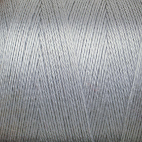 Close-up image of a spool of light gray 8/2 Tencel Yarn from Maurice Brassard. The tightly woven, thin threads create a smooth texture. The surface showcases a uniform, slightly shiny appearance, perfect for weaving projects and knitting accessories, highlighting the fine details of the individual strands.