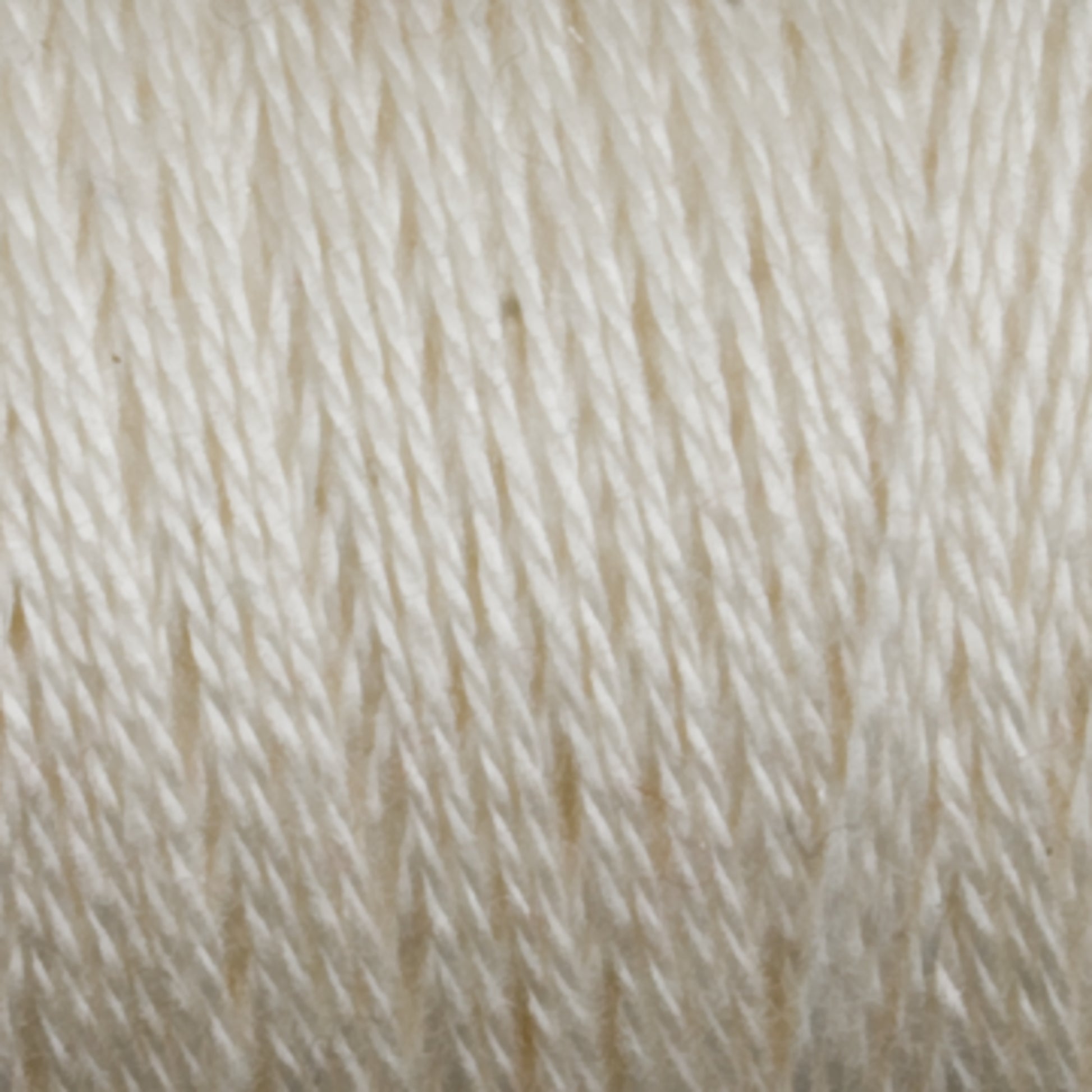 Close-up image of a spool of Maurice Brassard's 8/2 Tencel Yarn. The strands of yarn are tightly wound in a uniform pattern, highlighting the texture and slight shine of the material. Perfect for weaving projects, the individual fibers are visible, giving a sense of the yarn’s tightly braided construction.