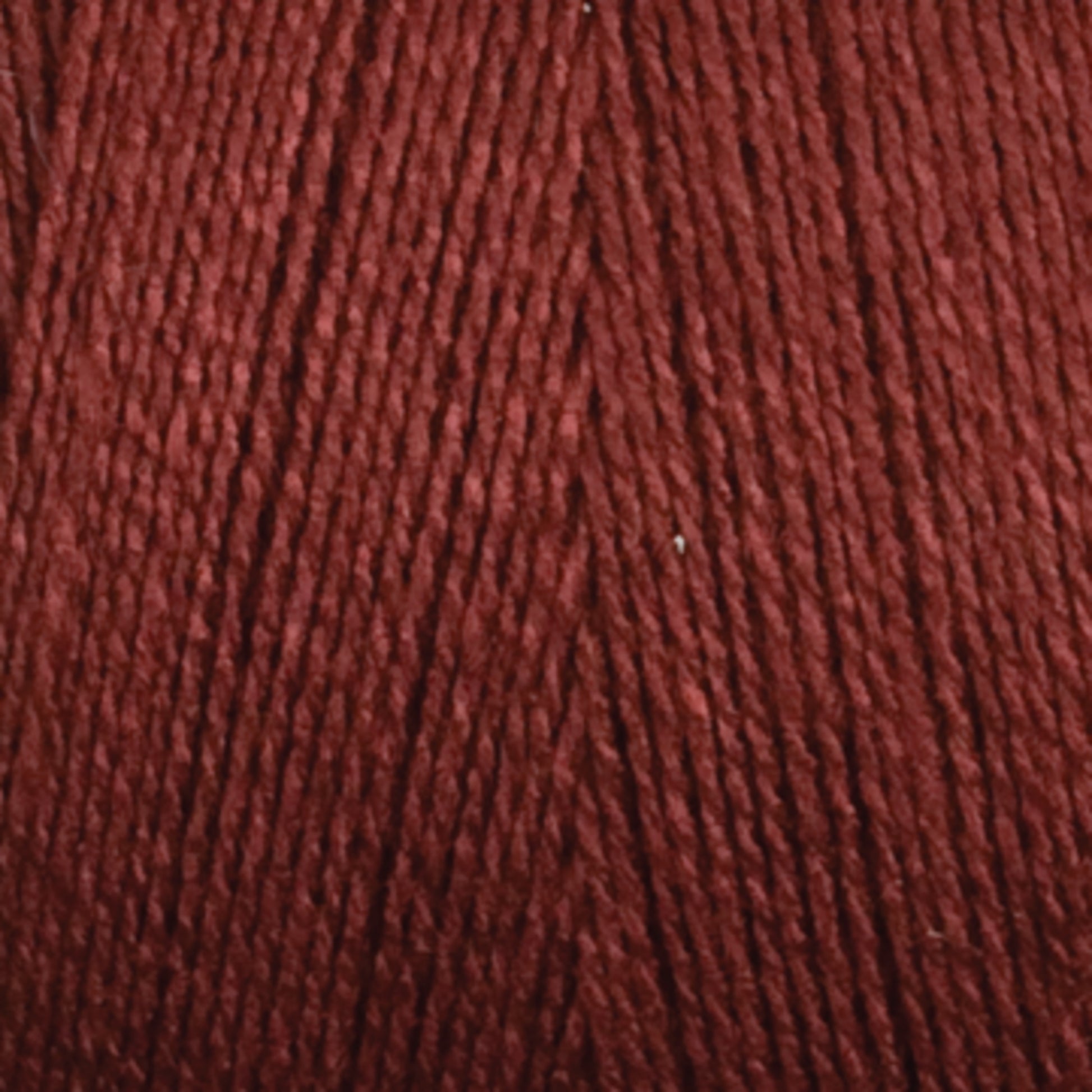 Close-up of a ball of Maurice Brassard's 8/2 Tencel Yarn | Tube in dark red, with tightly wound strands, showcasing its texture and color. The yarn appears smooth and evenly spun, perfect for weaving projects or knitting accessories, indicating it is made from high-quality Tencel yarn.