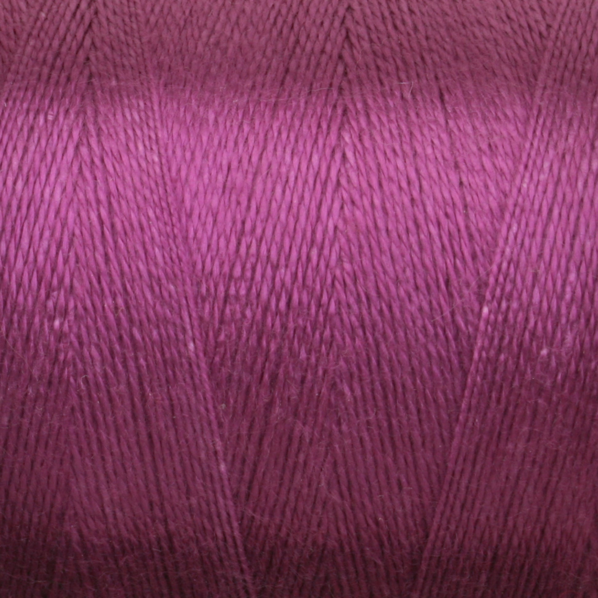 Close-up image of a spool of Maurice Brassard 8/2 Tencel Yarn | Tube in purple. The yarn is tightly wound, allowing the individual strands to be distinctly visible and showcasing a rich, vibrant color with a slight sheen. Ideal for weaving projects, the repetitive pattern creates a textured and detailed appearance.