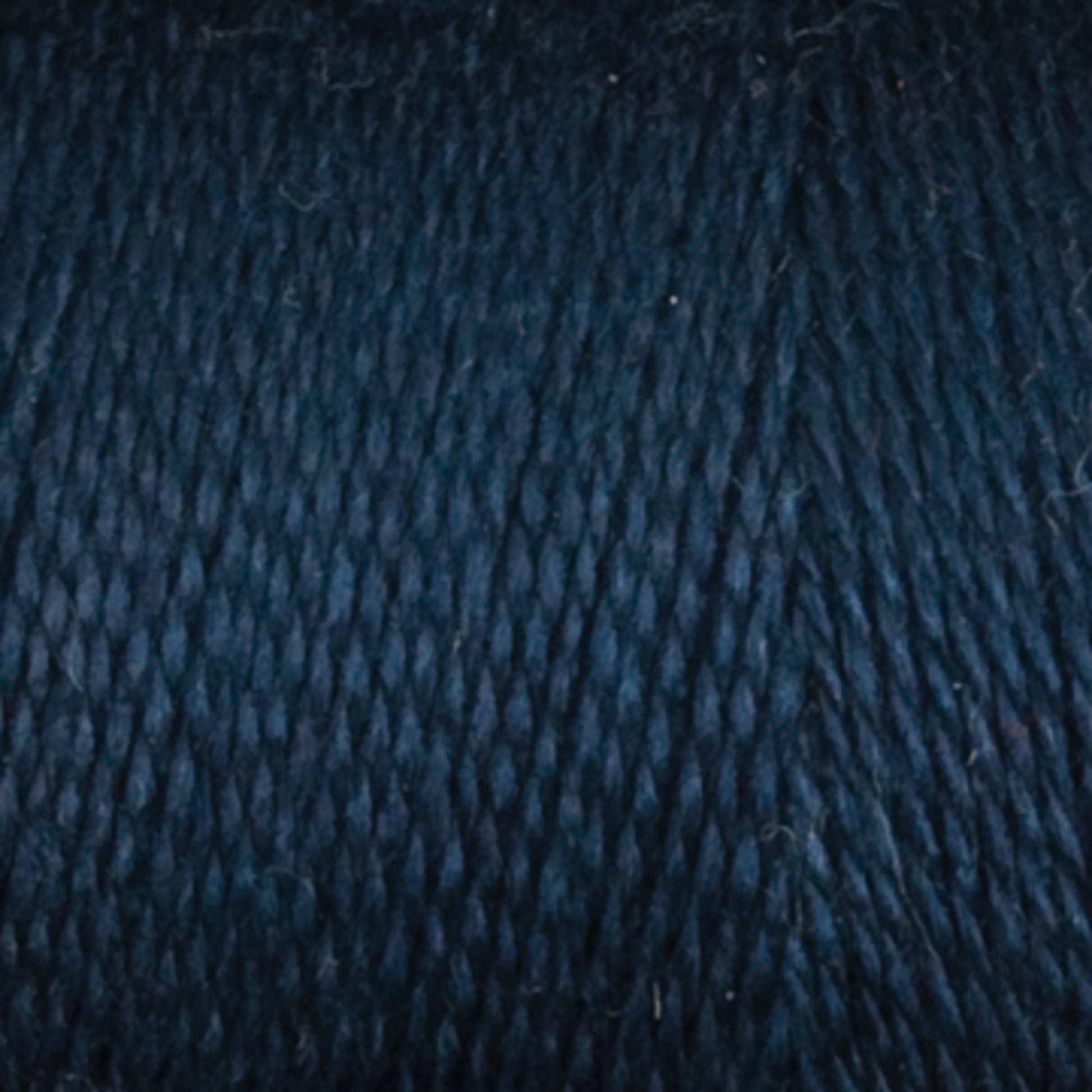 Close-up of Maurice Brassard's 8/2 Tencel Yarn in dark blue, showcasing its tightly wound texture and subtly varied shades. The fibrous surface makes it perfect for weaving projects or a great addition to your knitting accessories collection.