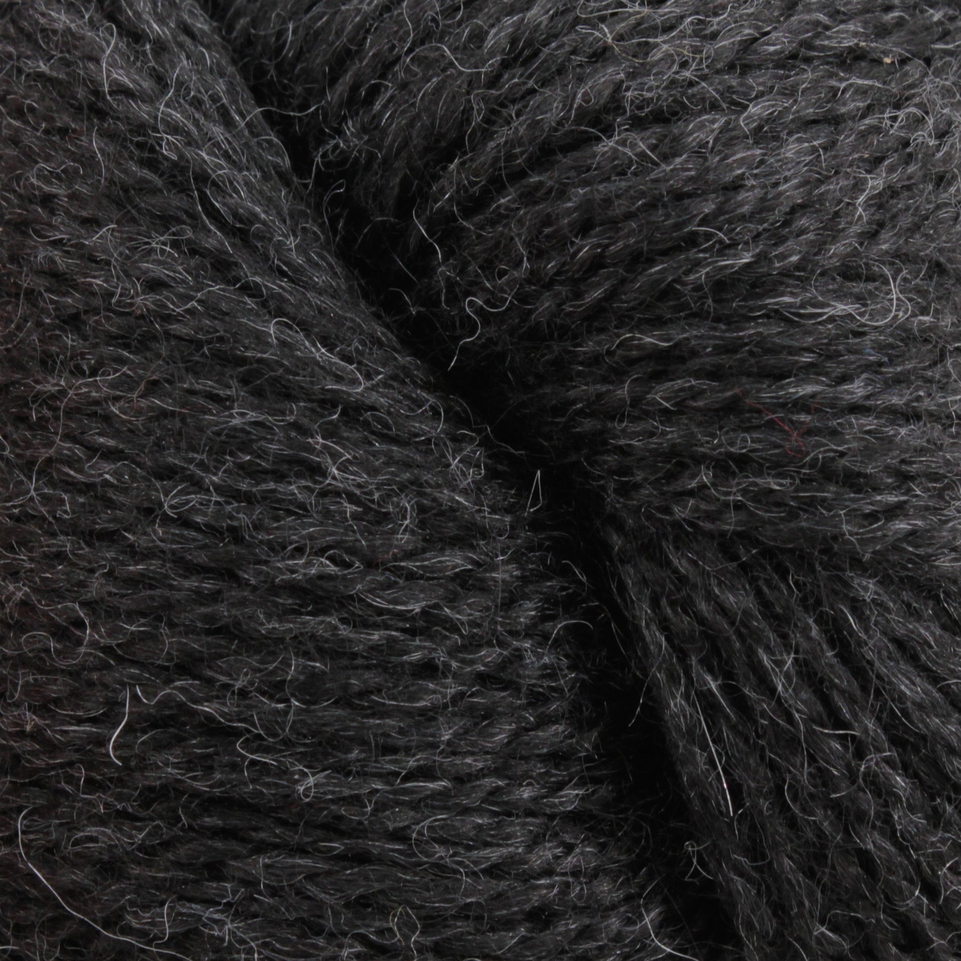 Close-up image of Herriot Fine Alpaca by Juniper Moon Farm in dark gray, showcasing its soft and fibrous texture with slight variations in color and fine strands interwoven tightly together. Ideal for creating sumptuous socks or lightweight accessories. This exquisite yarn is brought to you by Knitting Fever / Euro.