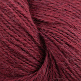 A close-up image of soft, deep red yarn fibers. The texture appears slightly fuzzy, with individual strands visible. Made from Baby alpaca, the Herriot Fine Alpaca by Juniper Moon Farm yarn is tightly wound, creating a cozy and warm appearance ideal for knitting sumptuous socks. This premium product is offered by Knitting Fever / Euro.