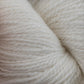 Close-up of a skein of the soft, cream-colored Herriot Fine Alpaca by Juniper Moon Farm yarn from Knitting Fever / Euro, showcasing its tightly spun fibers with impressive texture and detail. This Baby alpaca yarn appears cozy and perfect for knitting sumptuous socks or lightweight accessories.