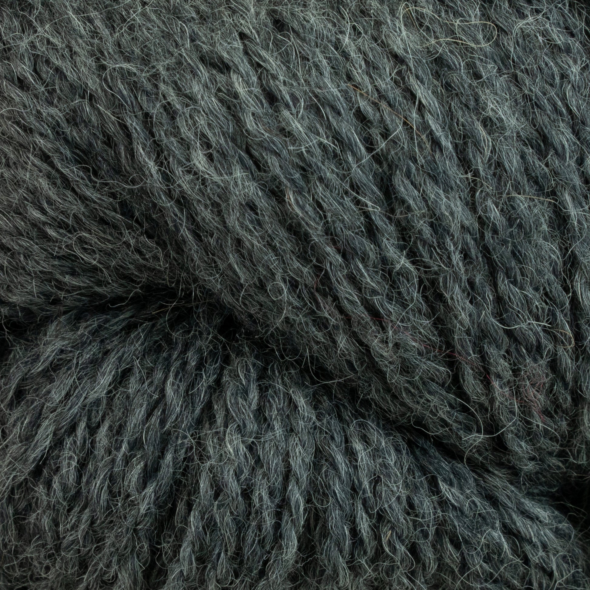 Close-up of Herriot Fine Alpaca by Juniper Moon Farm, a chunky, textured yarn in a dark green hue. The fibers from Knitting Fever / Euro appear soft, thick, and intricately intertwined with hints of baby alpaca, creating a cozy and inviting appearance suitable for knitting or crocheting sumptuous socks and warm garments.