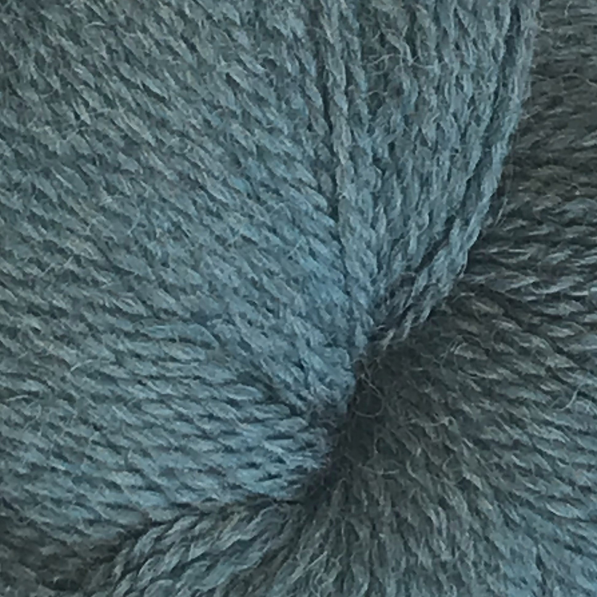 A close-up image of Herriot Fine Alpaca by Juniper Moon Farm in teal, crafted from baby alpaca, shows the texture and individual fibers of the material. The yarn is tightly wound, revealing a smooth and slightly fuzzy surface, making it perfect for creating sumptuous socks. This exquisite product is brought to you by Knitting Fever / Euro.