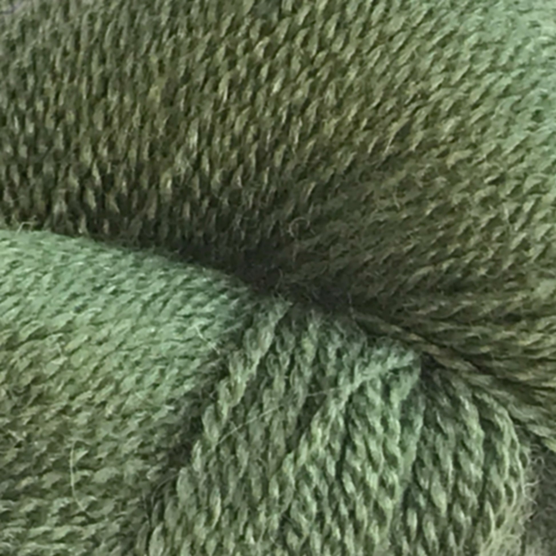 Close-up view of a green skein of the Herriot Fine Alpaca by Juniper Moon Farm yarn from Knitting Fever / Euro, showcasing the detailed texture and strands tightly woven together, perfect for crafting lightweight accessories.