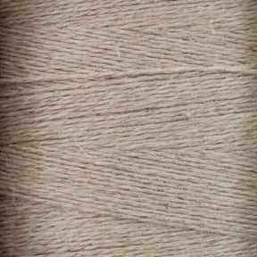 Close-up image of Halcyon Yarn's Newport 16/2 Linen Yarn on a large cone. The tightly wound strands showcase the coarse, somewhat uneven texture of the natural fiber, reminiscent of genuine linen. The overall appearance is uniform, with subtle variations in the thickness and shade of the strands.