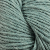 Close-up of Moonshine yarn by Juniper Moon Farm from Knitting Fever / Euro in a thick, light teal shade with visible fibers and a slightly fuzzy texture. The strands, made from a blend of wool and alpaca, are tightly wound together, showcasing the softness and warmth of the material.