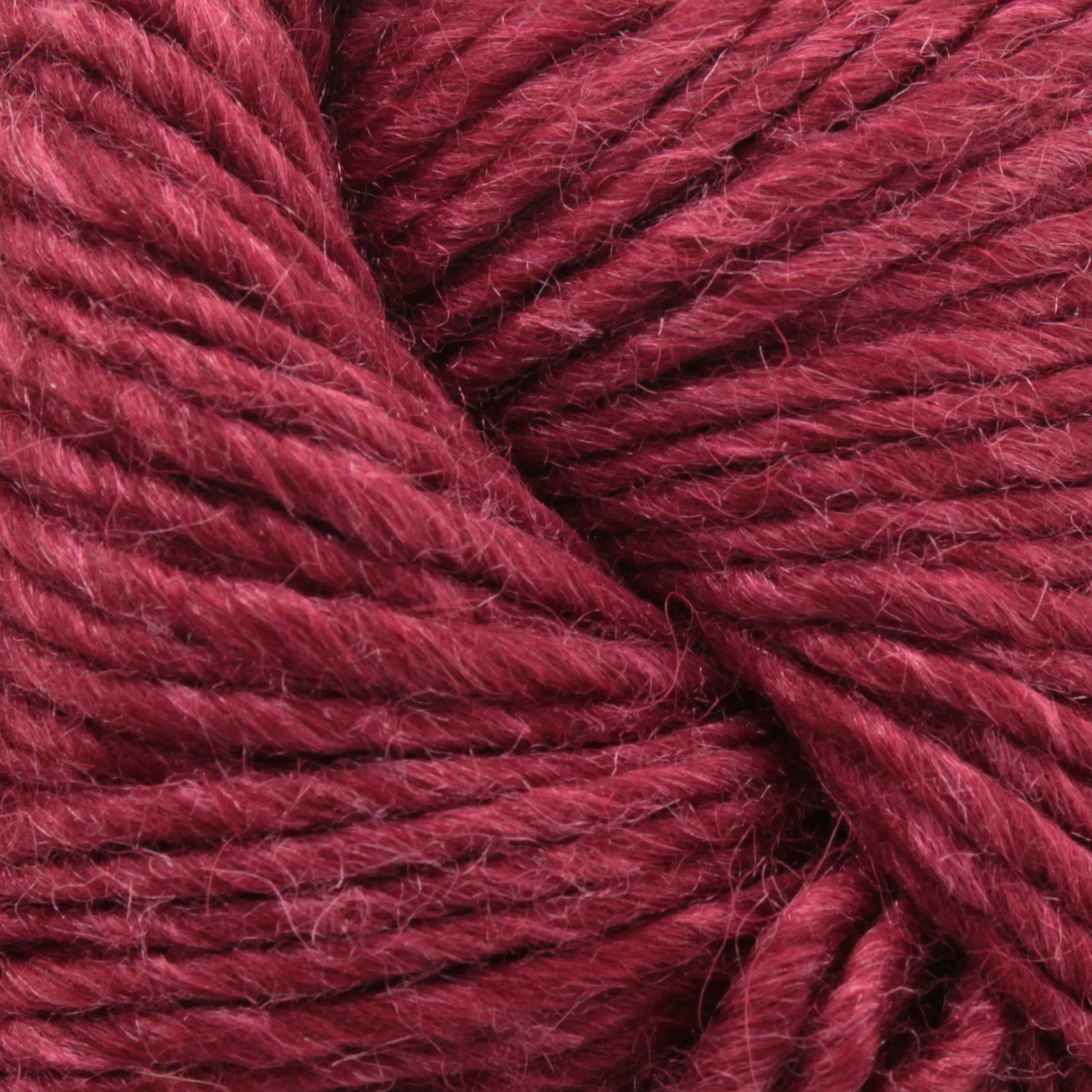 Close-up of a skein of Moonshine by Juniper Moon Farm from Knitting Fever / Euro. The texture showcases tightly spun strands with a slight fuzzy halo, hinting at its wool blend. The rich color and detailed fibers are prominently displayed, emphasizing the softness and thickness of this luxurious yarn.