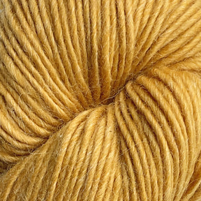 Close-up image of a ball of chunky, golden-yellow yarn—Moonshine by Juniper Moon Farm. The texture of the wool fibers is clearly visible, showcasing twists and slight fuzziness characteristic of high-quality wool from Knitting Fever / Euro. The yarn is tightly wound in a circular pattern.