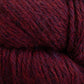 Close-up of Juniper Moon Farm Herriot Baby Alpaca yarn by Knitting Fever / Euro, featuring a deep reddish-purple hue with complex, interwoven strands. The DK weight fibers are thick and slightly fuzzy, showcasing the rich color variations and the soft, cozy material of extrafine baby alpaca.