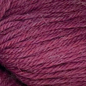 Close-up image of magenta-colored Juniper Moon Farm Herriot Baby Alpaca yarn with a soft texture and visible fibers. The extrafine baby alpaca strands, crafted by Knitting Fever / Euro, are tightly wound, showcasing the DK weight yarn's detail and thickness.