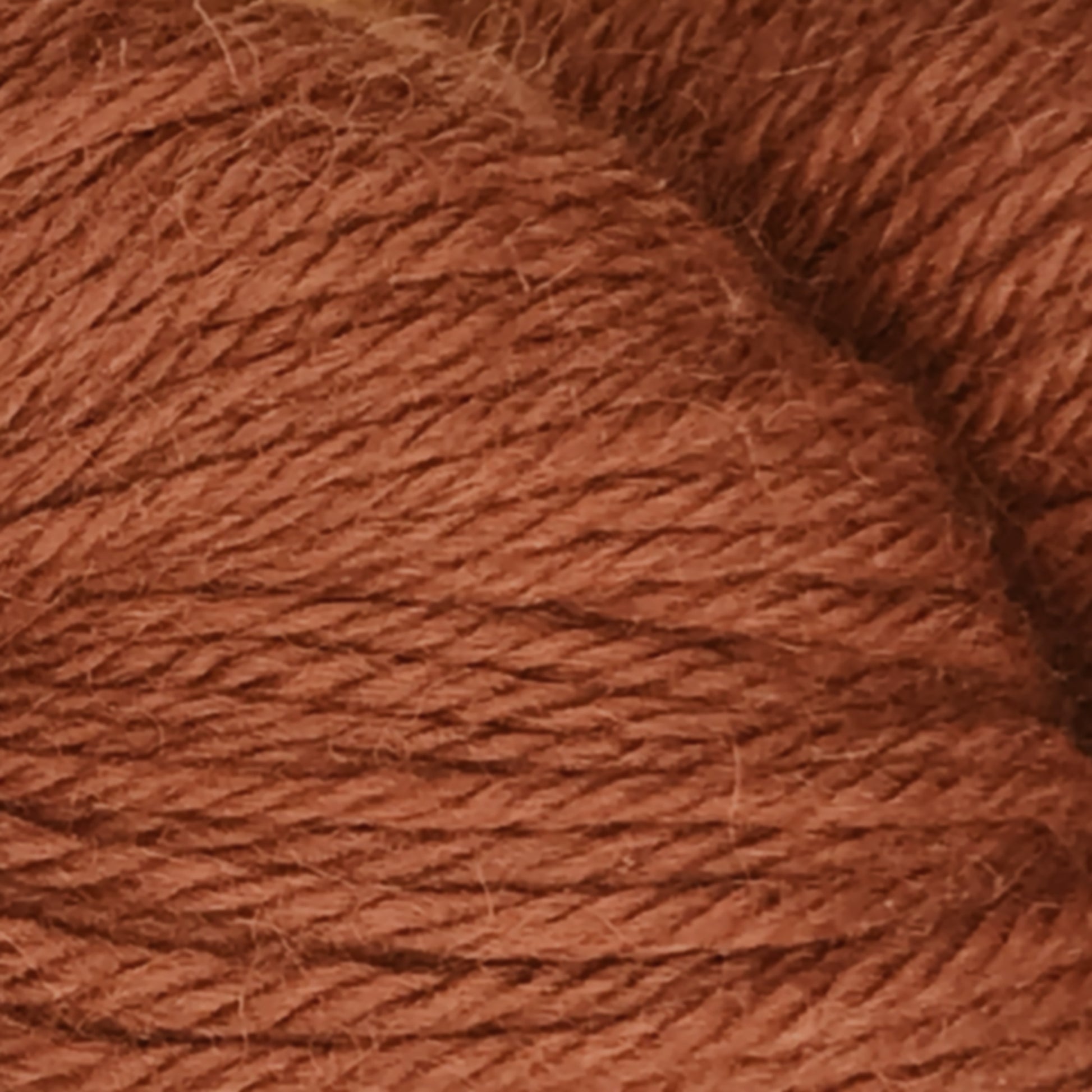 Close-up image of a ball of Juniper Moon Farm Herriot Baby Alpaca yarn. The texture is clearly visible, showing the intertwined strands of DK weight yarn. The overall appearance is soft and fibrous with a warm, earthy brown color. Product by Knitting Fever / Euro.