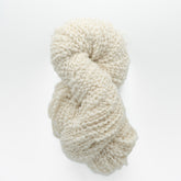 Polar Bear Yarn by Henry's Attic is a chunky skein of soft, off-white, textured weaving yarn. Loosely twisted into a spiral, it appears fluffy with slightly irregular thickness, offering a rustic and cozy appeal for knitters against a plain white background.