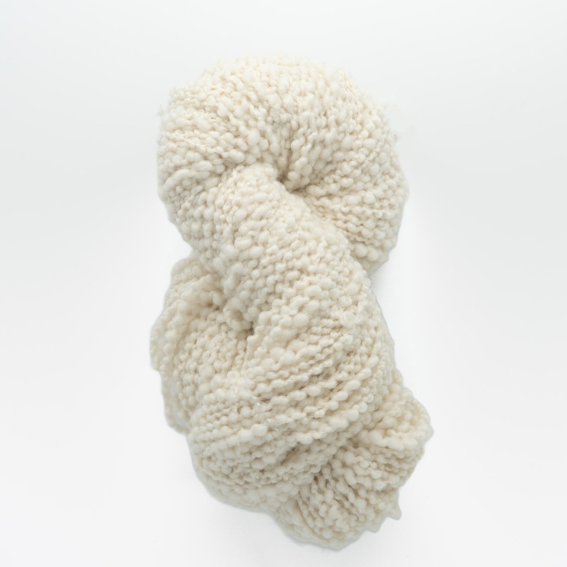 Polar Bear Yarn by Henry's Attic is a chunky skein of soft, off-white, textured weaving yarn. Loosely twisted into a spiral, it appears fluffy with slightly irregular thickness, offering a rustic and cozy appeal for knitters against a plain white background.