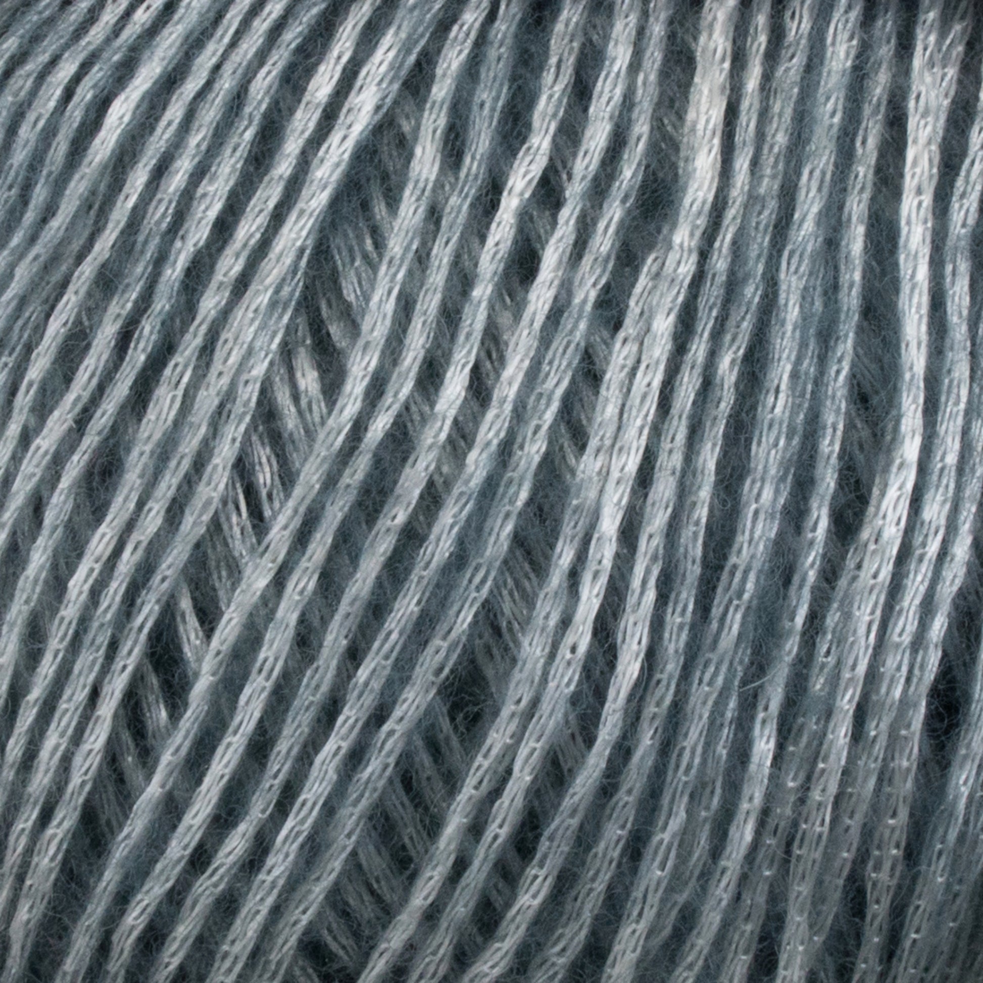 A close-up image of Katia Air Lux fingering weight Merino wool fibers, tightly woven together, showing the texture and strands in fine detail. The fibers have a slightly shiny appearance, reflecting light softly. The overall image gives a sense of softness and intricacy to the Knitting Fever / Euro brand yarn.