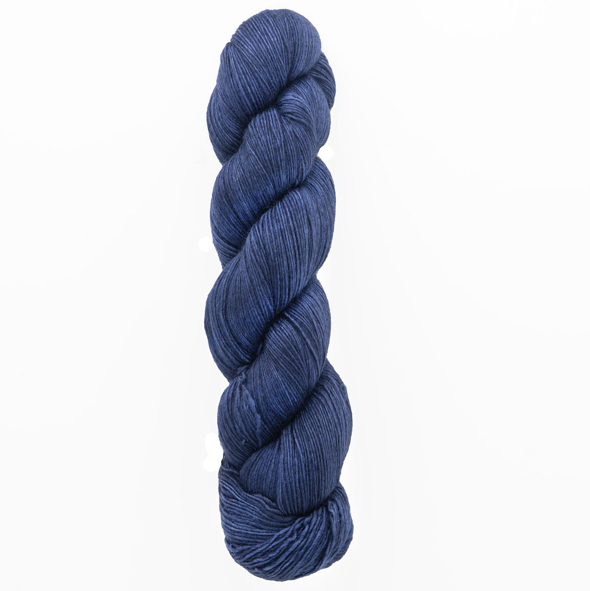 A skein of deep blue Malabrigo Lace by Malabrigo Yarn is coiled neatly against a plain white background. This yarn, ideal for knitted shawls, appears soft and tightly wound, highlighting its rich color and texture.