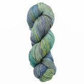 A skein of Malabrigo Sock yarn from Malabrigo Yarn, showcasing versatile kettle-dyed shades of green, blue, and hints of yellow, is twisted into a neat spiral against a white background.