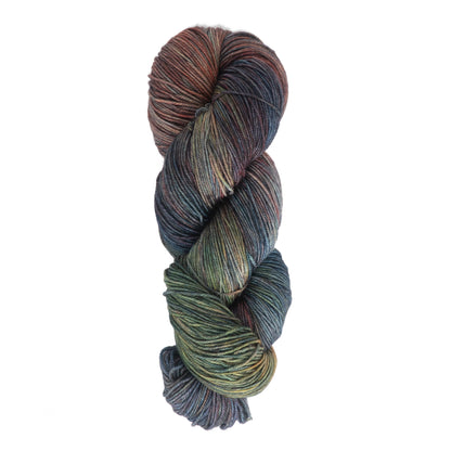 A skein of Malabrigo Sock yarn by Malabrigo Yarn, featuring a blend of earthy tones such as green, brown, blue, and hints of purple. The Merino wool yarn is neatly twisted, showcasing the variegated colors and the soft, smooth texture. Plus, it’s machine washable for easy care.