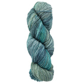 A skein of Malabrigo Yarn's Arroyo, crafted from soft merino wool, showcases a captivating mix of variegated blue-green shades, spanning from light seafoam to deep teal and neatly twisted into a tight coil. This sport weight yarn is ideal for your next cozy project.